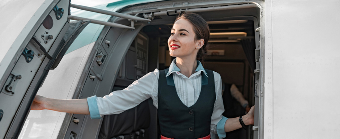 Azafata de pie en la puerta del avión.