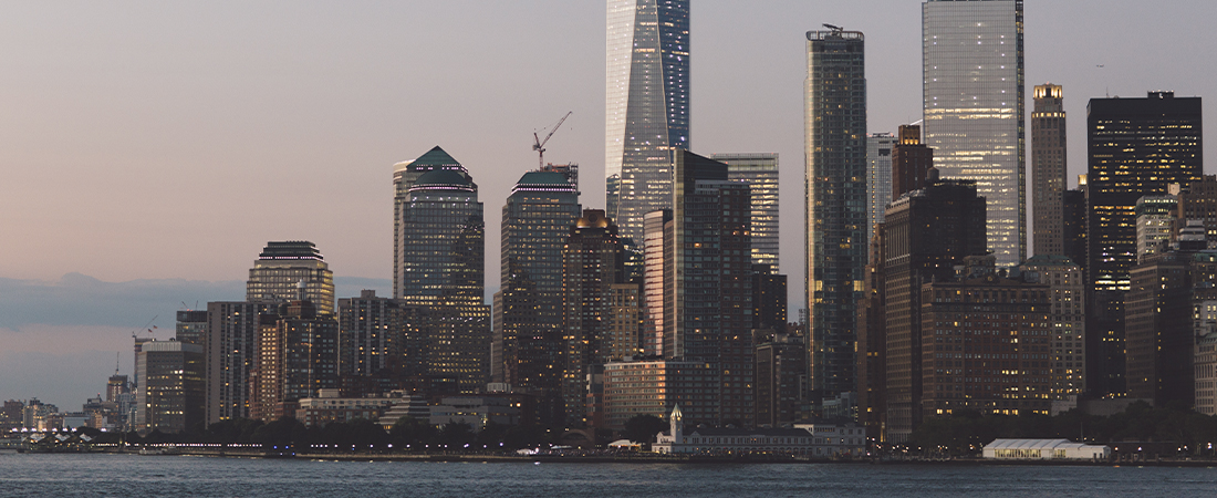 Panorámica de los rascacielos y el perfil urbano de Nueva York al atardecer frente al agua.